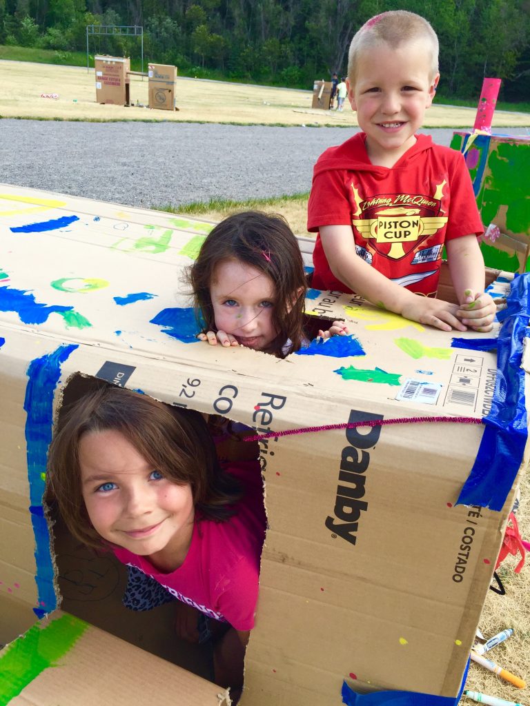 An image of three students creating art using a box