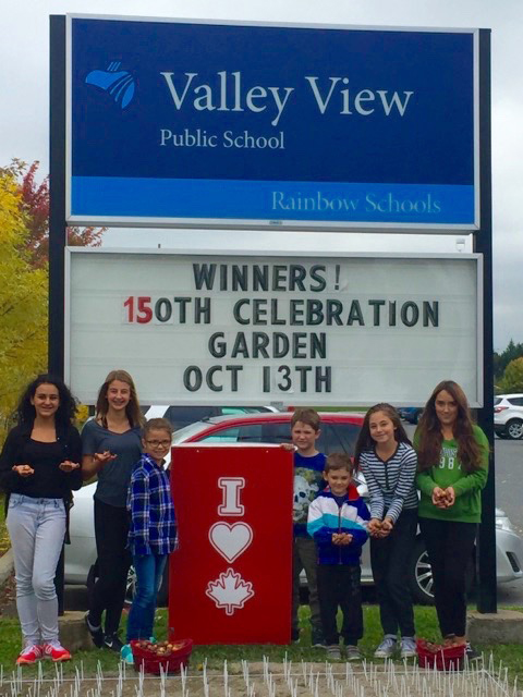 Valley View Public School students standing in front of the school sign holding tulip bulbs