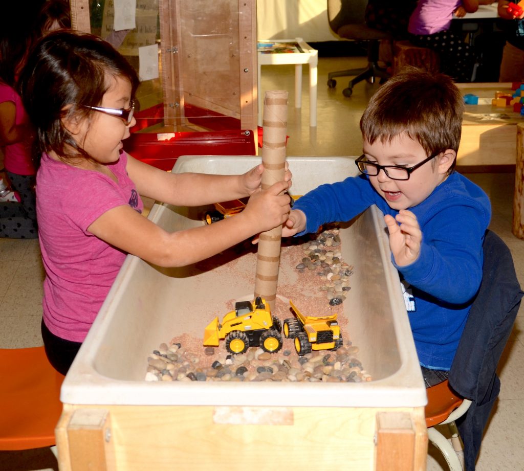 Two students work together to build a structure from paper towel rolls.