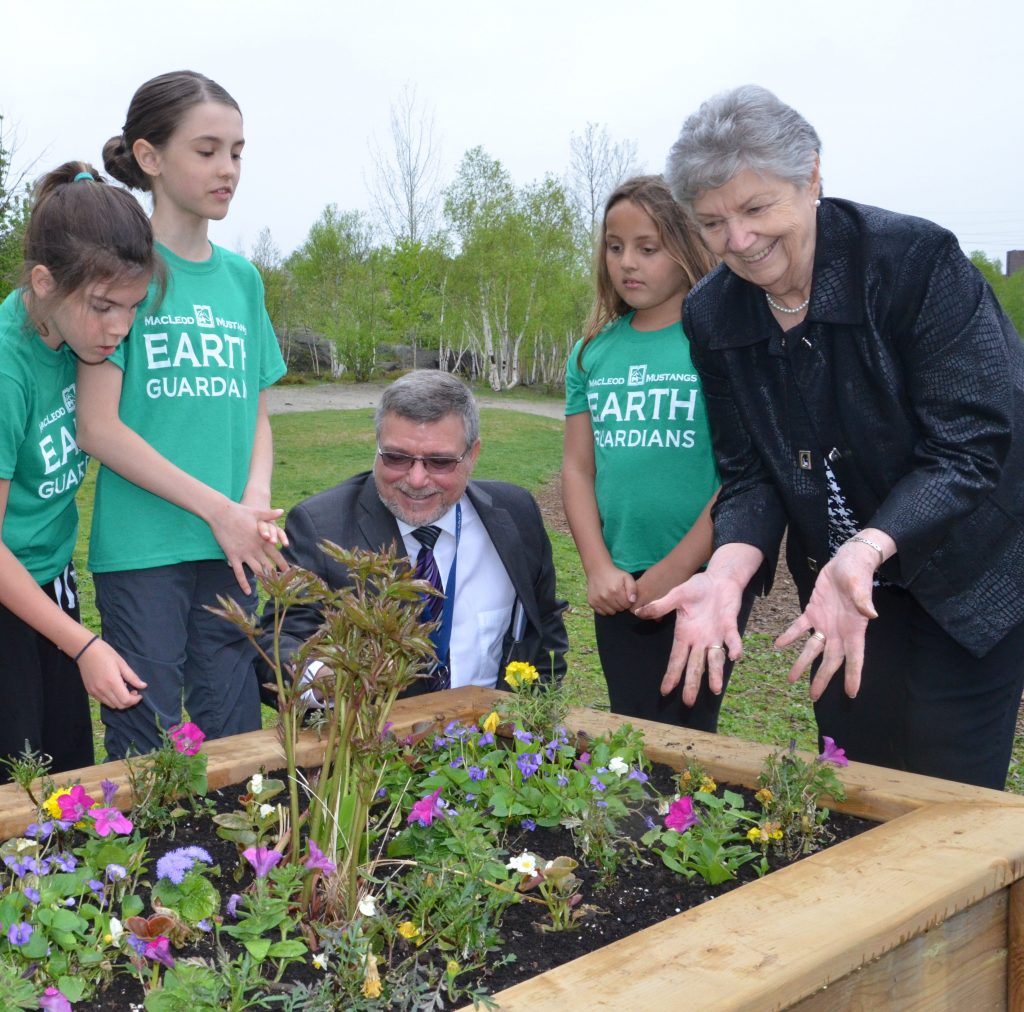 rainbow officials in front of a flower bed