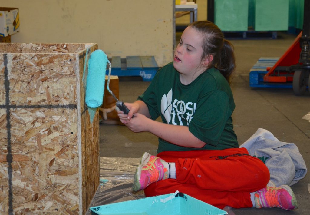 a student painting a wooden box