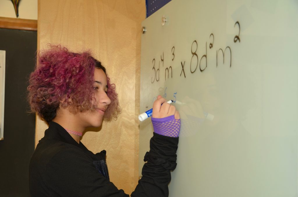 a student practicing math on a whiteboard