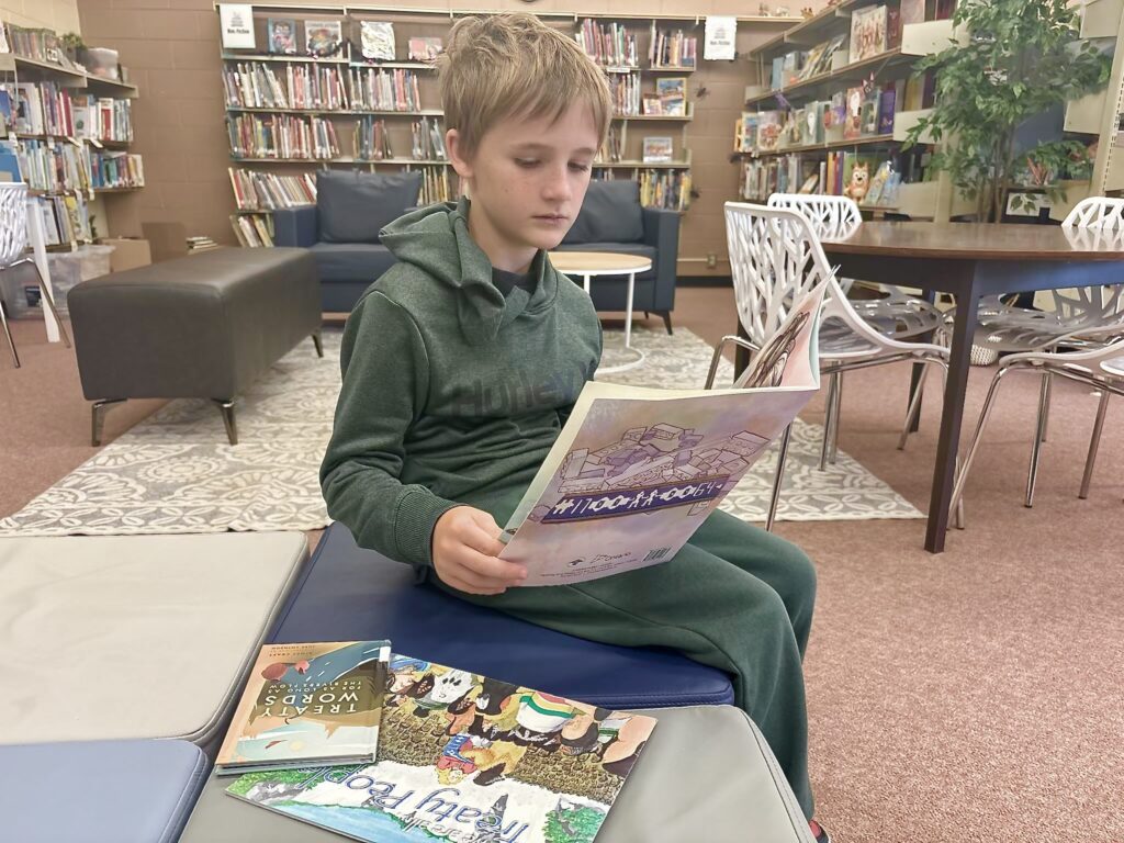 Grade 5 student Brycen Turner of Monetville Public School reads Kelly Crawford’s “Alex Shares his Wampum Belt” in the school library.